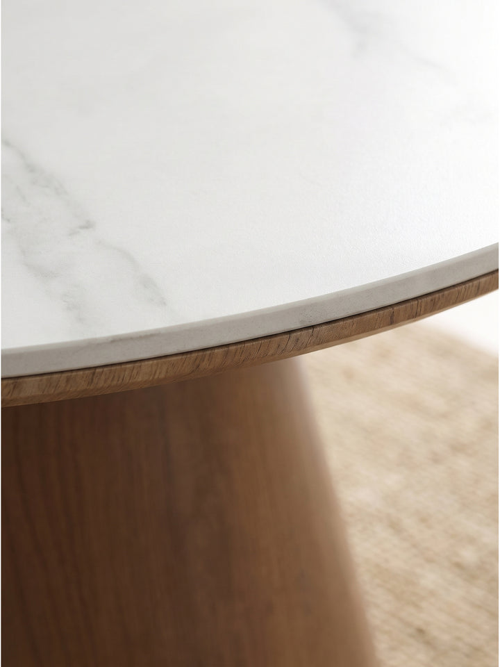 Nahaufnahme der weißen pflegeleichten Sinterstein-Tischplatte mit filigraner grauer Marmorierung und dem robusten Kegelgestell in edler Holzoptik_