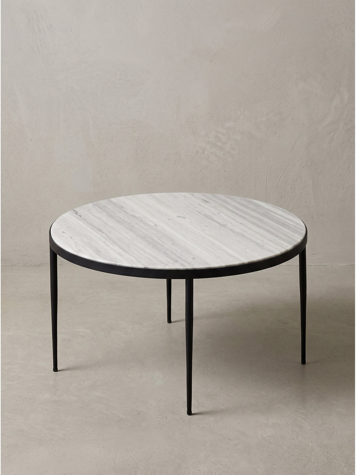 Runder Sofatisch im puristischen Design mit schwebender Steinoptik und stabilem Eisenrahmen aus seitlicher Perspektive fotografiert.