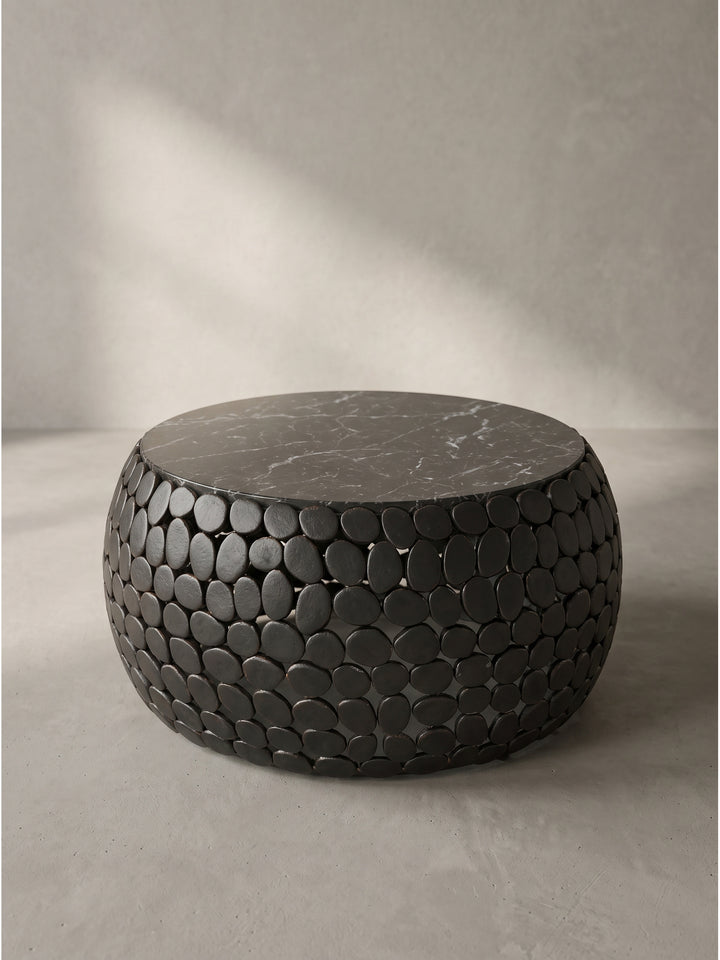 Design-Wohnzimmertisch aus hochwertigem Marmor und durchbrochenem Metall aus seitlicher Perspektive auf weißem Hintergrund._
