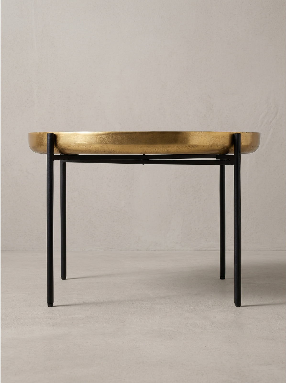 Profilansicht des runden Kaffeetisches mit einer 6 cm starken goldenen Platte auf einem minimalistischen Eisengestell