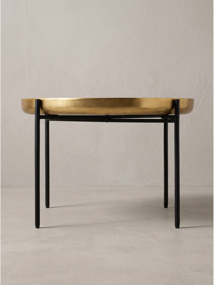 Profilansicht des runden Kaffeetisches mit einer 6 cm starken goldenen Platte auf einem minimalistischen Eisengestell_