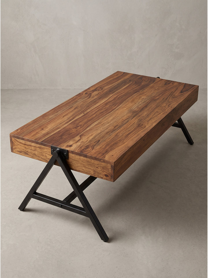 Halbschräge Ansicht des massiven Wohnzimmertisches, die seine 10 cm starke Holzplatte und die robuste schwarze Metallkonstruktion deutlich zeigt._