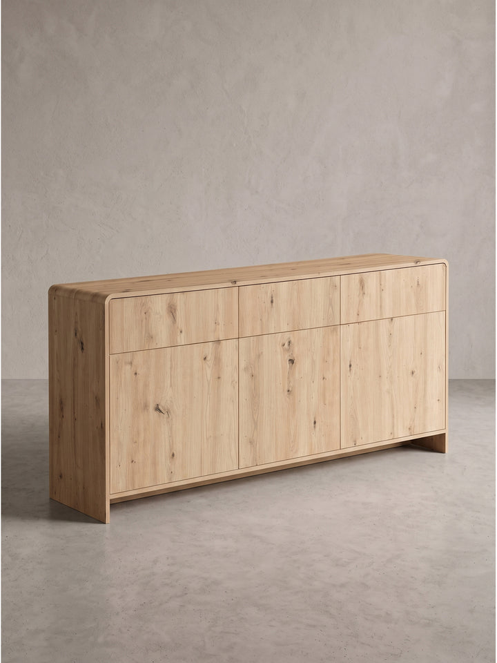 Perspektivische Darstellung des Eiche Dekor Sideboards von rechts, die das warme natürliche Finish des Holzwerkstoffs hervorhebt._