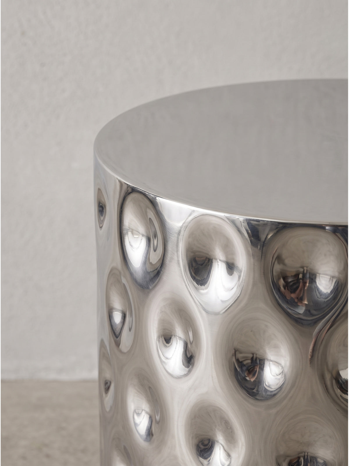 Eine weitere Ansicht des außergewöhnlichen Aluminium-Beistelltisches verdeutlicht die luxuriöse Ausstrahlung der stark strukturierten, silbernen Oberfläche.