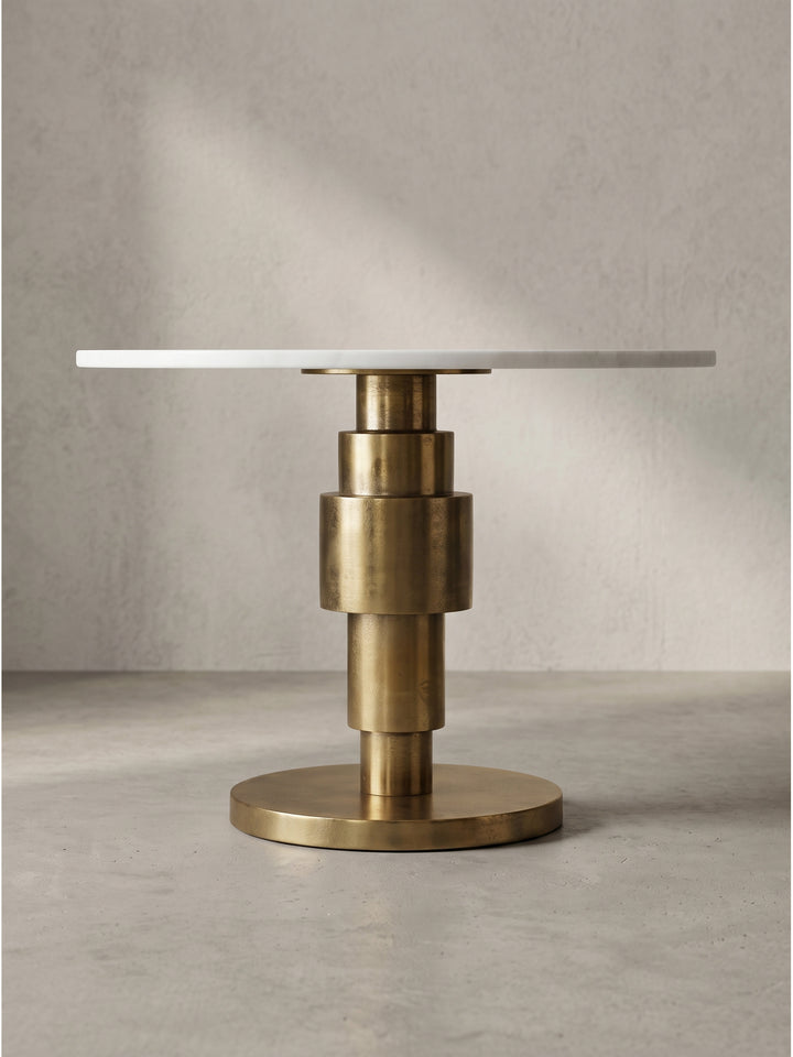 Leicht seitliche Perspektive des Art-Deco Wohnzimmertisches, die den glänzenden Aluminiumfuß und die weiße Steinplatte eindrucksvoll zeigt_