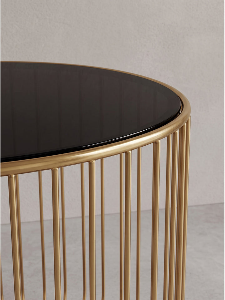 Erhöhte Schrägansicht des modernen Sofatischs, die den architektonischen Kontrast zwischen dunkler Platte und goldenem Gitter verdeutlicht._