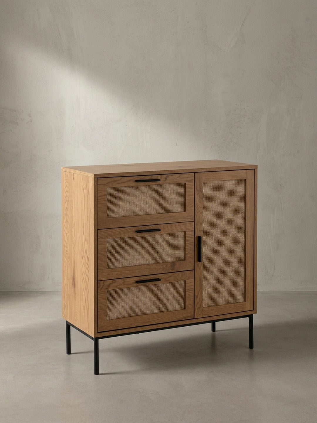 Schräge 3/4-Ansicht des Sideboards mit Rattan-Einsätzen, die die Tiefe des Möbels und das Zusammenspiel von Holzdekor und schwarzen Metallgriffen hervorhebt._