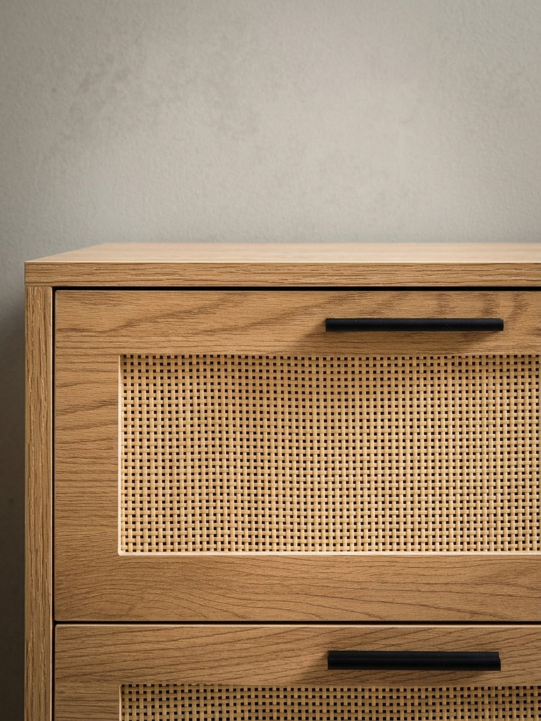 Detailaufnahme eines der schwarzen, pulverbeschichteten Metallgriffe an einer Schublade mit Rattan-Front, die die hochwertige Verarbeitung und moderne Haptik zeigt._