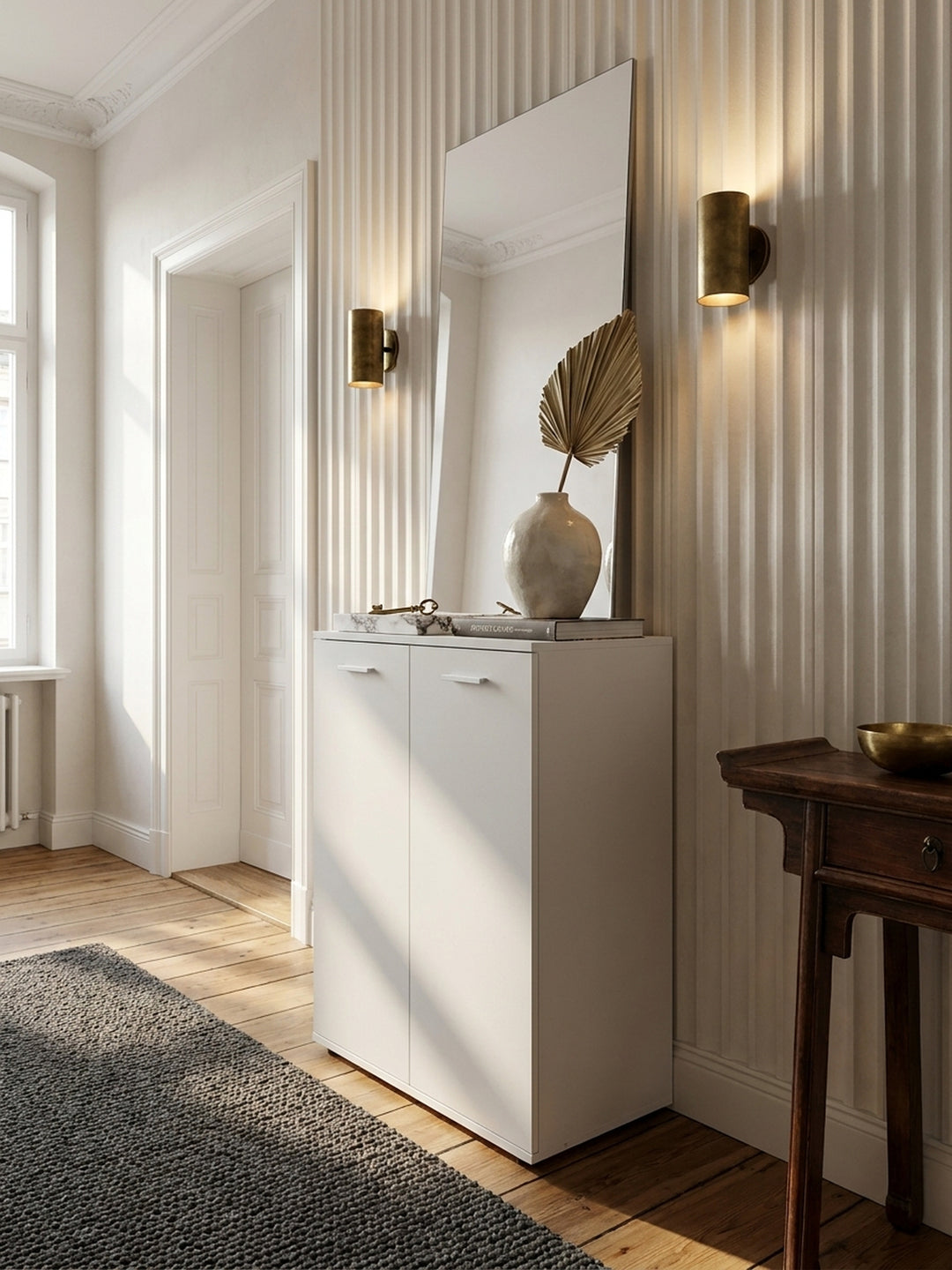 Kompakte Flurkommode neben einer eleganten Garderobe aus dunklem Holz auf einem tiefgrauen Bouclé-Teppich im luxuriösen, reduzierten Entrée_