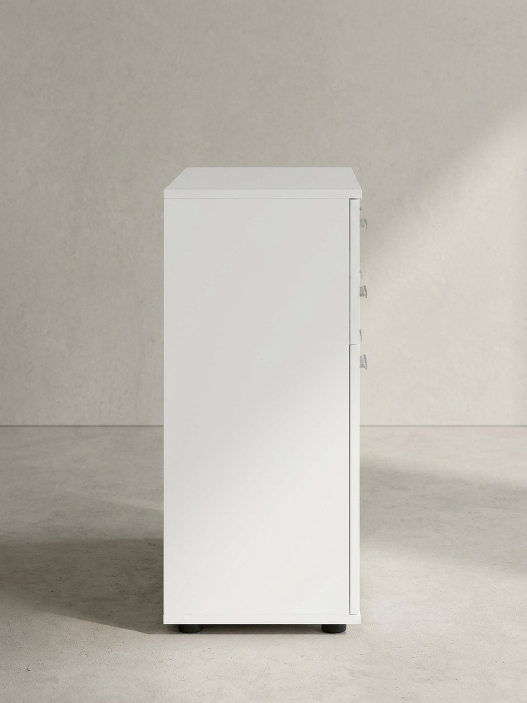 Moderner Beistellschrank mit matten weißen Oberflächen und silbernen Griffdetails leicht schräg aus der Frontperspektive abgelichtet._