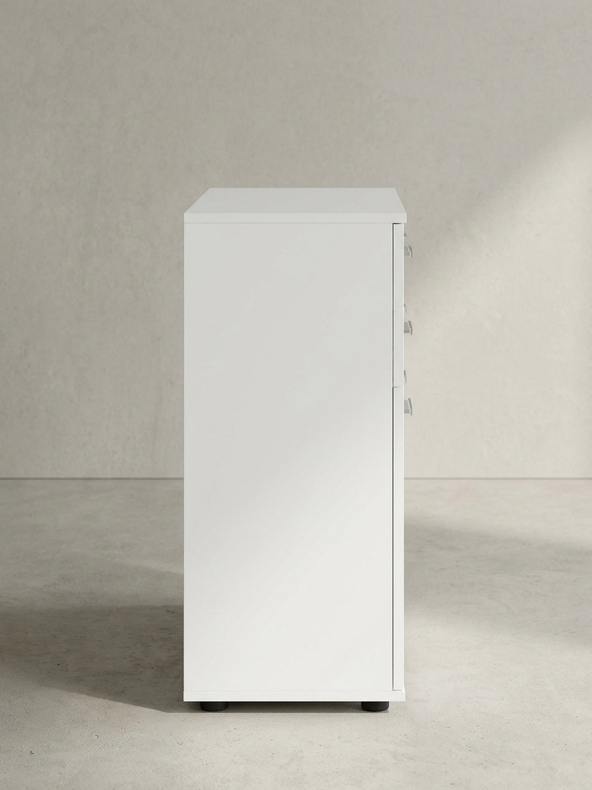 Moderner Beistellschrank mit matten weißen Oberflächen und silbernen Griffdetails leicht schräg aus der Frontperspektive abgelichtet._
