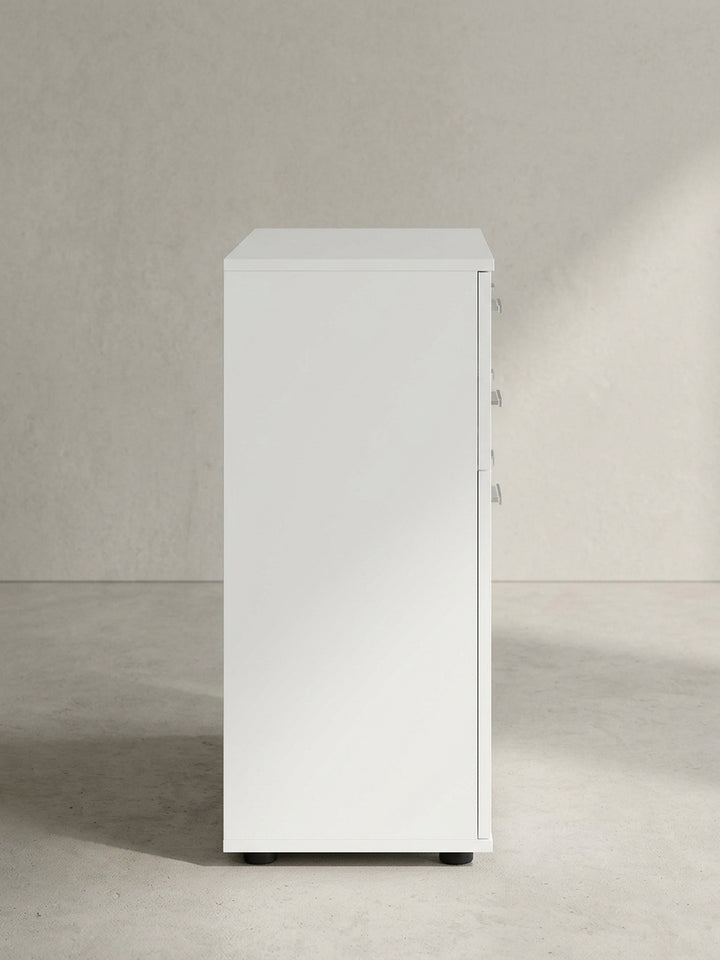 Moderner Beistellschrank mit matten weißen Oberflächen und silbernen Griffdetails leicht schräg aus der Frontperspektive abgelichtet._