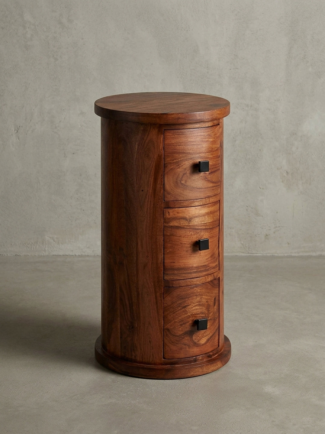 Freigestellte Frontalansicht der runden Kommode mit 3 Schubladen aus Sheesham-Holz. Das schlanke Design und die schwarzen Griffe des 65 cm hohen Schranks sind gut sichtbar._