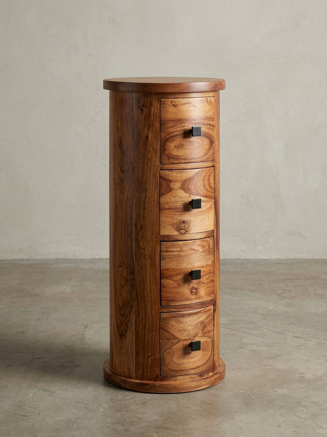 Design Beistellschrank aus massivem Sheesham-Holz in 3/4-Ansicht, die zylindrische Form und die geschwungenen Schubladenfronten zeigend._