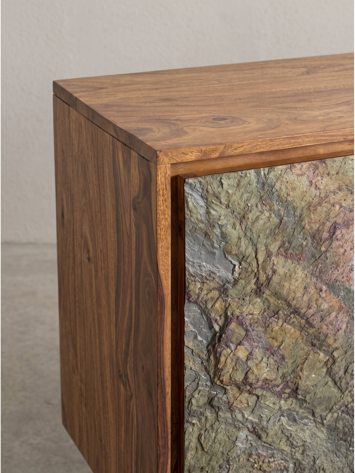 Alternative Perspektive des Sideboards mit Fokus auf den Kontrast zwischen rötlichem Holz und der rauen Steinstruktur der Türen_