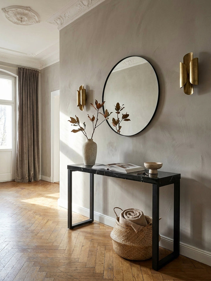 Eleganter Konsolentisch in schwarzer Marmor-Optik im Flur einer Altbauwohnung, stilvoll dekoriert mit einer Vase und Büchern auf Fischgrätparkett._