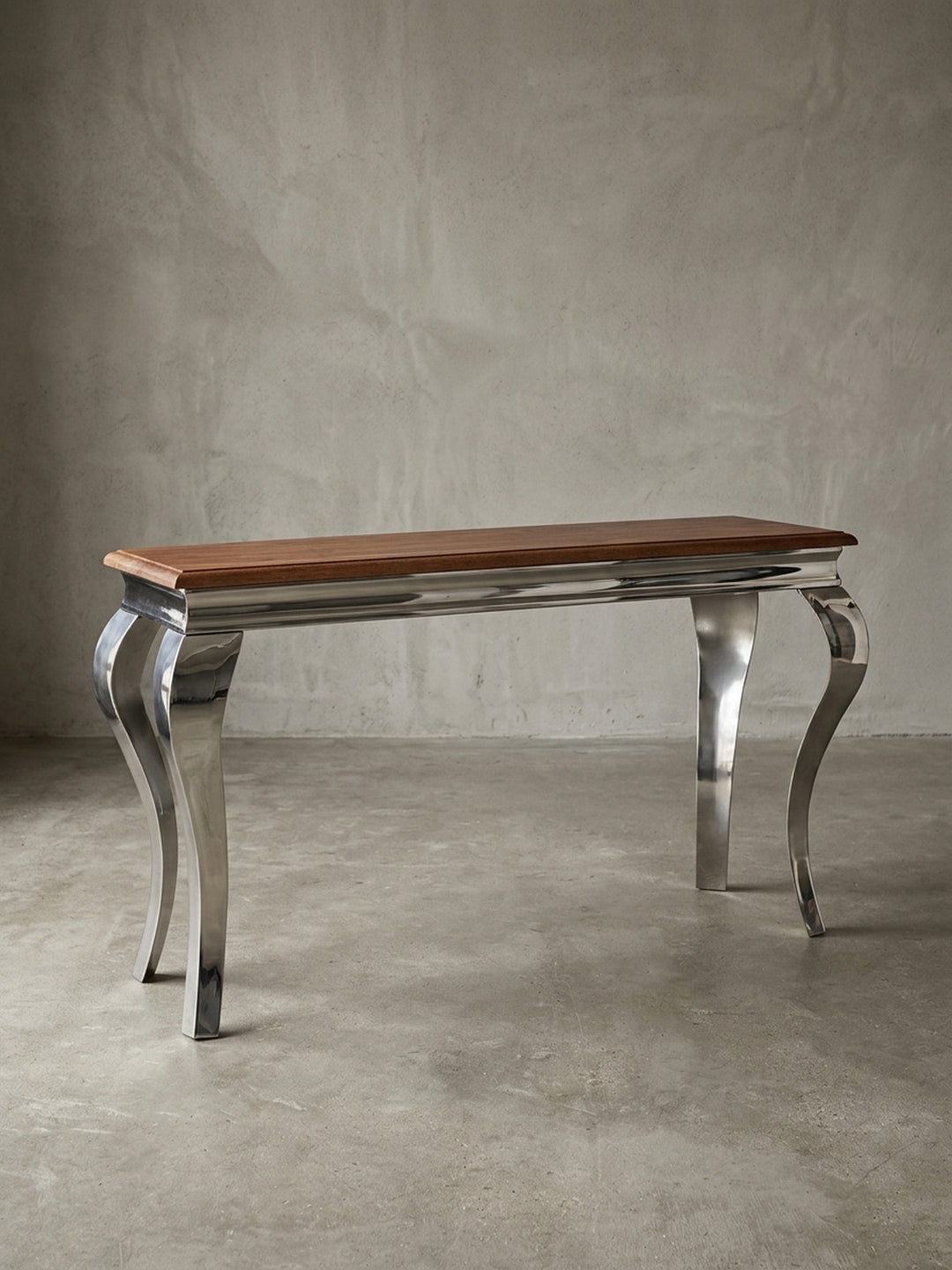 Moderner Konsolentisch freigestellt in der Frontalansicht. Die 130x76 cm große Anrichte kombiniert eine massive Echtholzplatte mit vier glänzenden, barock geschwungenen Metallbeinen._