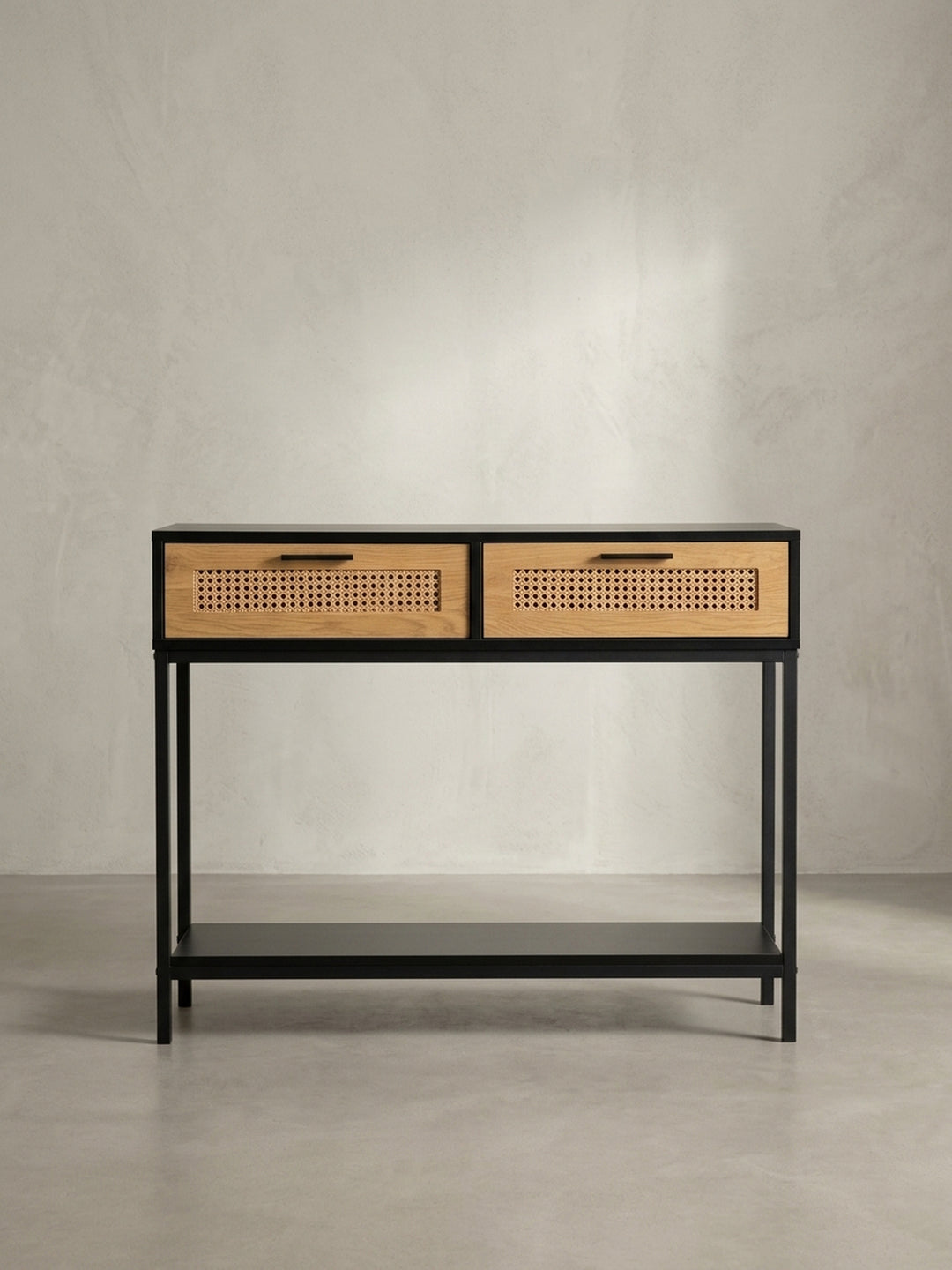 Schräger Blick auf den Design Konsolentisch, der die Kombination aus schwarzem Korpus und naturfarbenen Rattan-Schubladen zeigt._