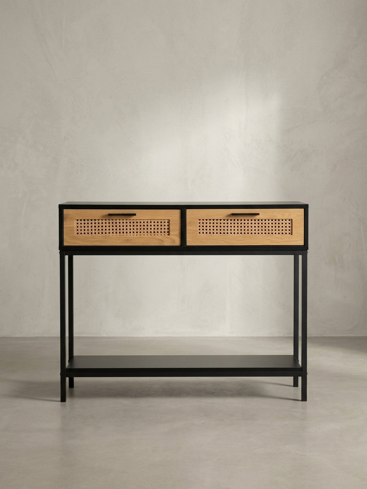 Schräger Blick auf den Design Konsolentisch, der die Kombination aus schwarzem Korpus und naturfarbenen Rattan-Schubladen zeigt._