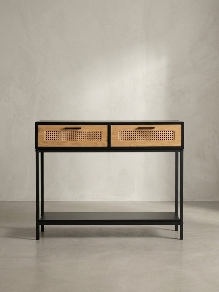 Schräger Blick auf den Design Konsolentisch, der die Kombination aus schwarzem Korpus und naturfarbenen Rattan-Schubladen zeigt._
