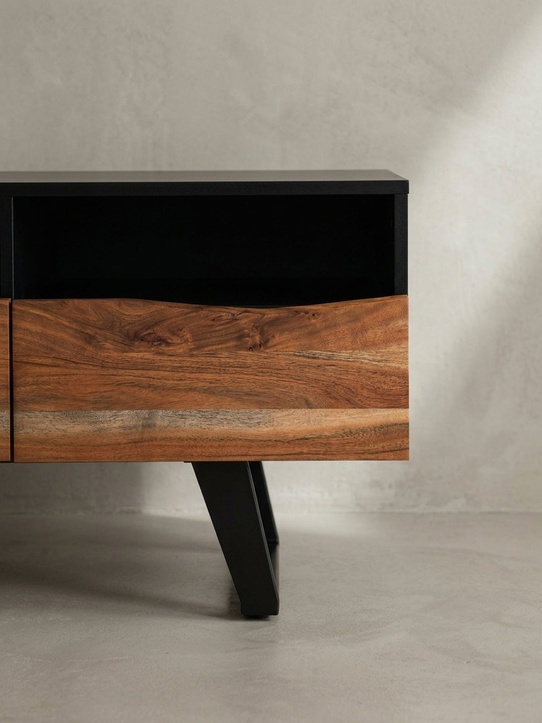 Perspektivische Ansicht des Akazie Massivholz Lowboards, die das Zusammenspiel zwischen den live-edge Fronten und dem geradlinigen schwarzen Rahmen verdeutlicht._