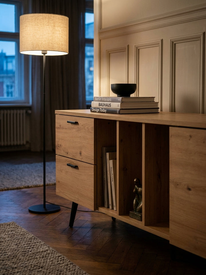 Stilvoll dekoriertes TV-Board mit Büchern und kleiner Pflanze in den offenen Regalbereichen unter einem großen Flachbildschirm._