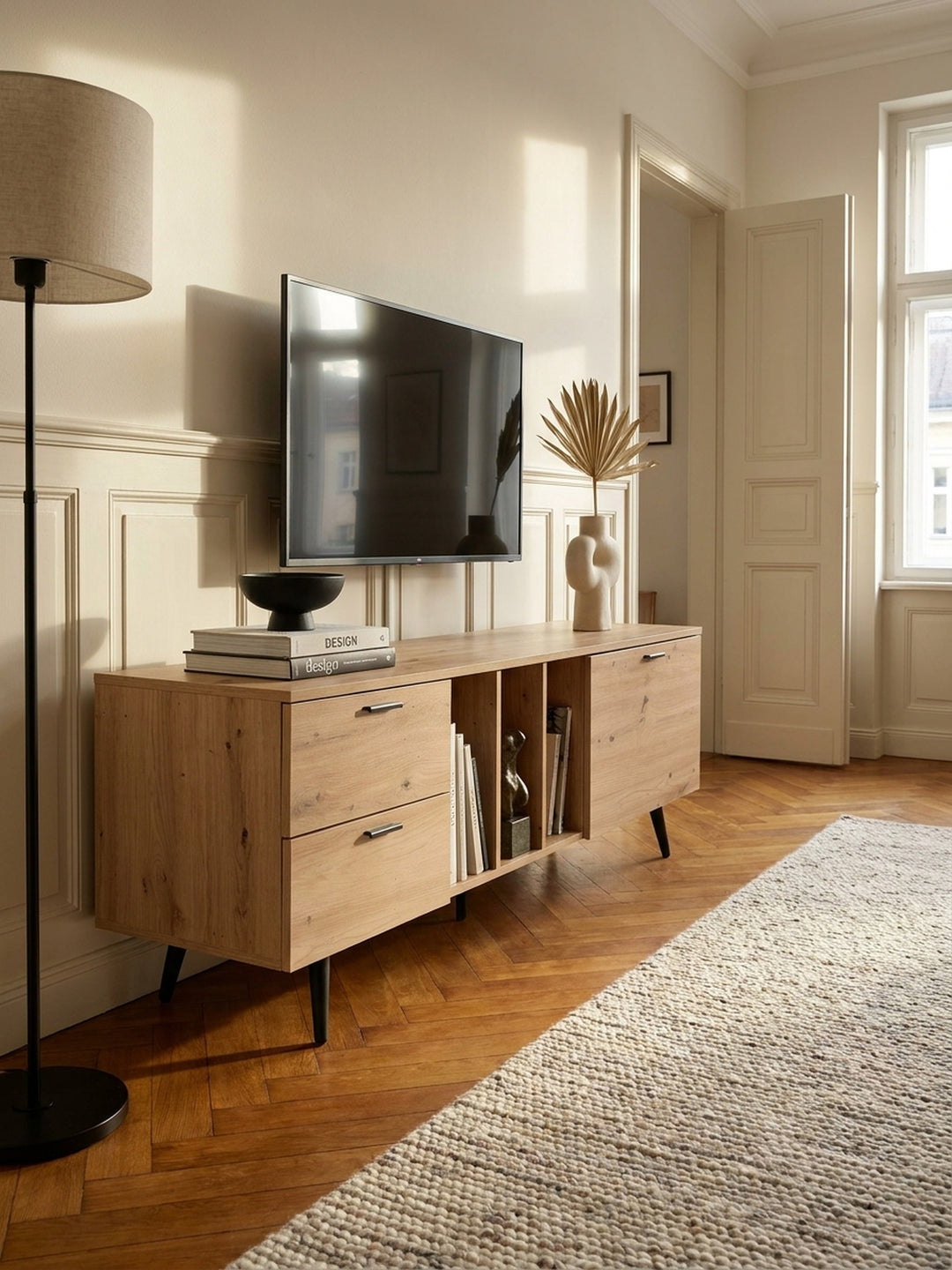 Nahaufnahme der Holzmaserung des folierten Eiche-Dekors mit mattschwarzem Metallgriff an der Schublade des Fernsehschranks._