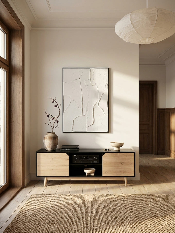 Weitläufige Ansicht eines minimalistischen Wohnzimmers im Japandi-Stil mit einem Lowboard in Schwarz und Eiche-Dekor unter einem gerahmten Kunstwerk._