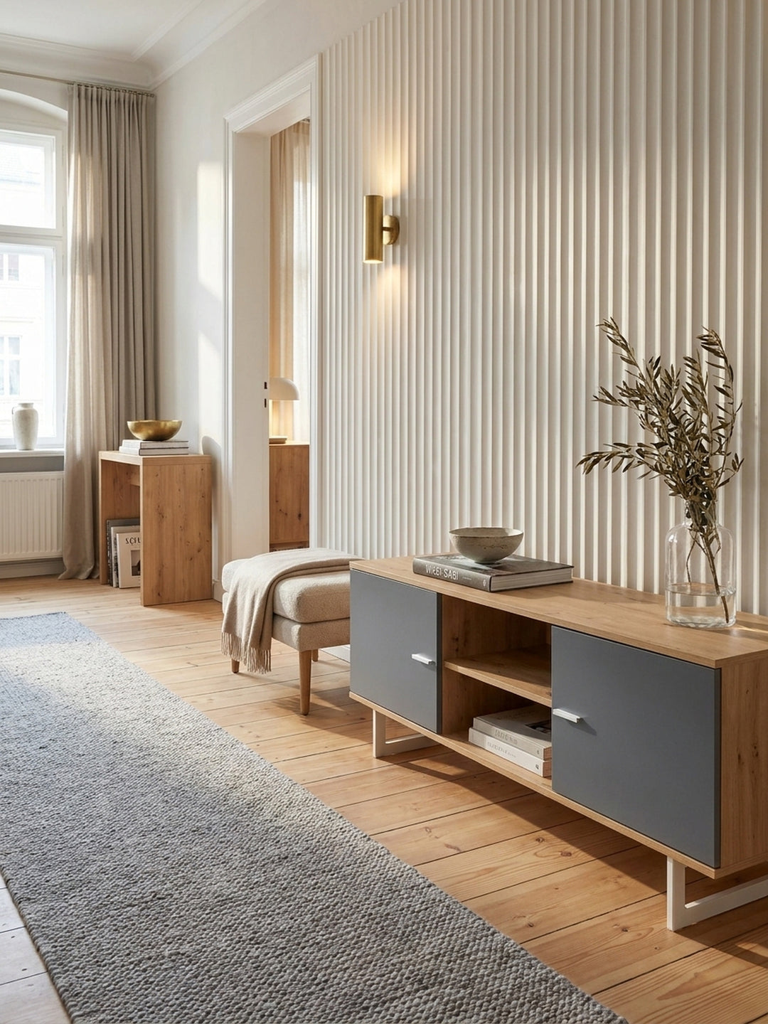 TV-Unterschrank in Eiche-Nachbildung harmonisch kombiniert mit einem handgewebten grauen Wollteppich und minimalistischer Messingbeleuchtung._
