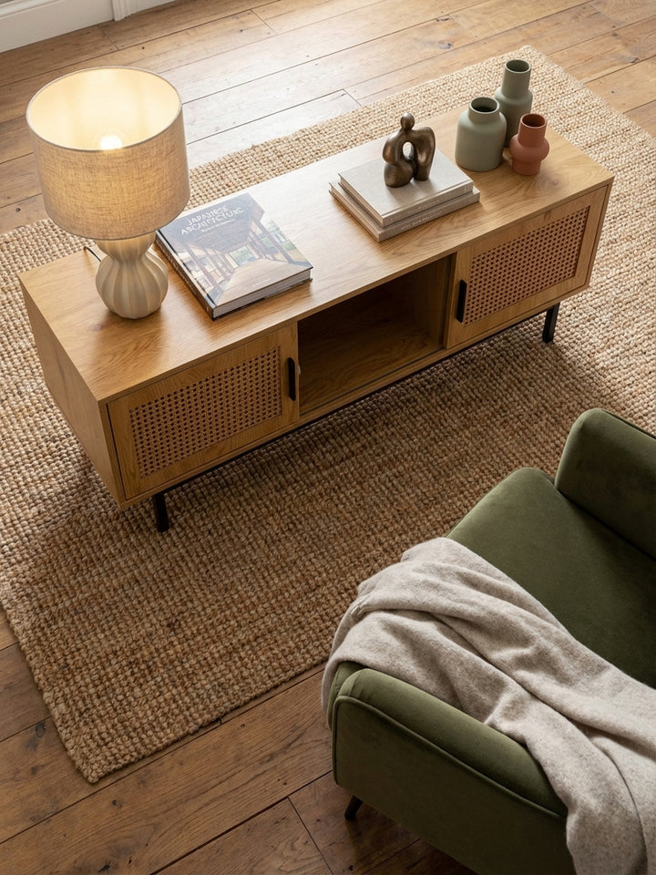 Ansicht von oben auf ein Wohnzimmer-Arrangement mit dem 120 cm breiten Fernsehschrank im Mittelpunkt, der durch seine Rattan-Türen eine natürliche Textur einbringt._