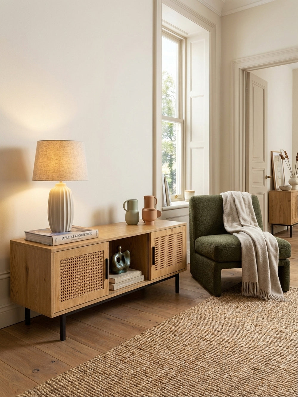 Zeitloses TV-Lowboard in Eiche-Optik mit Wiener Geflecht, stimmungsvoll in einem modernen Wohnzimmer mit Jute-Teppich und einer Leselampe inszeniert._