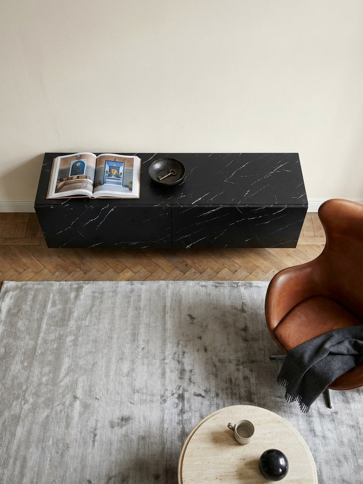 Draufsicht auf das 120 cm breite TV-Lowboard aus MDF, arrangiert mit einem hellen Beni Mrirt Teppich und einem Ledersessel in einem Altbau-Wohnzimmer._