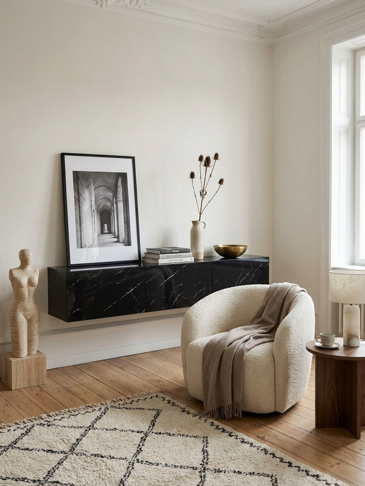 Das hängende TV-Lowboard in schwarzer Marmor-Optik harmoniert mit einem modernen Ledersessel und minimalistischer Wanddekoration in einem stilvollen Wohnambiente._
