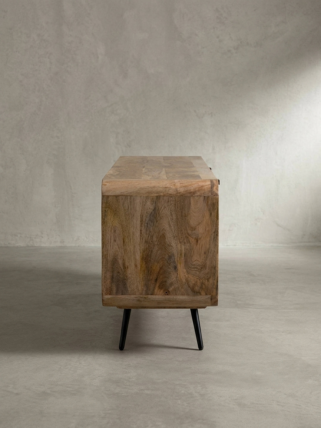 Gesamtansicht des Design-TV-Unterschranks aus Massivholz und Metall, der die harmonische Materialkombination und die hochwertige Verarbeitung unterstreicht._
