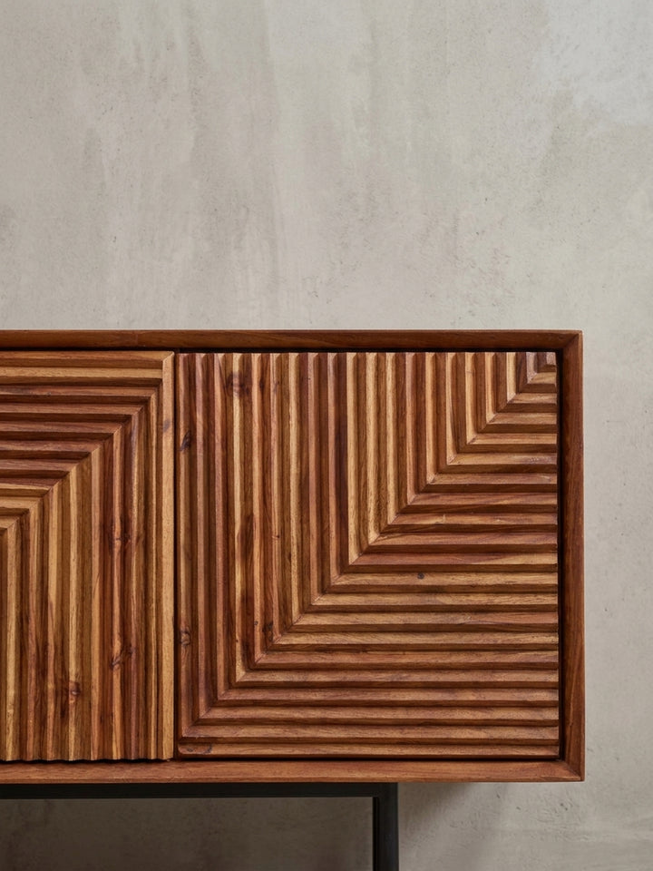 Detailaufnahme der schwarzen T-förmigen Metallfüße, die einen stabilen Stand und einen modernen Kontrast zum Massivholz-Korpus des Lowboards bieten._