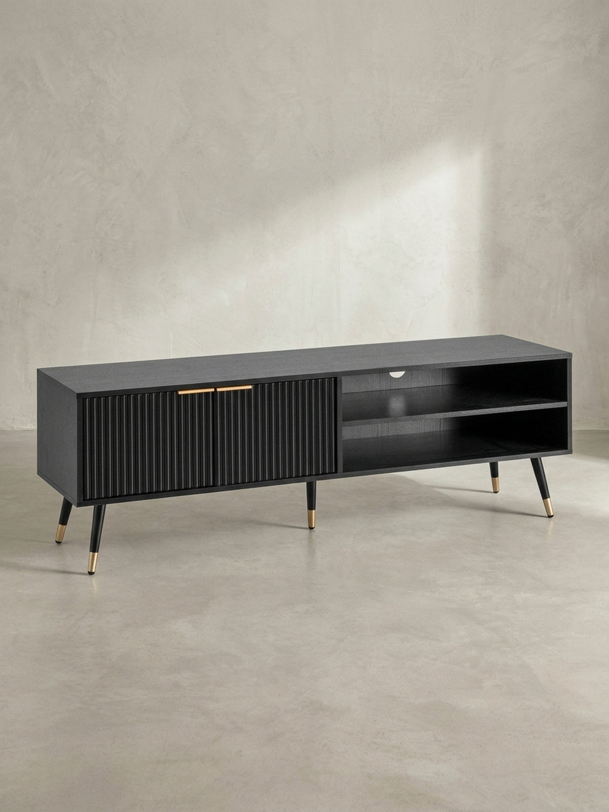 Schräge Seitenansicht der schwarzen TV-Kommode, die die Tiefe der offenen Fächer und das Design der schrägen Beine mit Goldkappen zeigt.