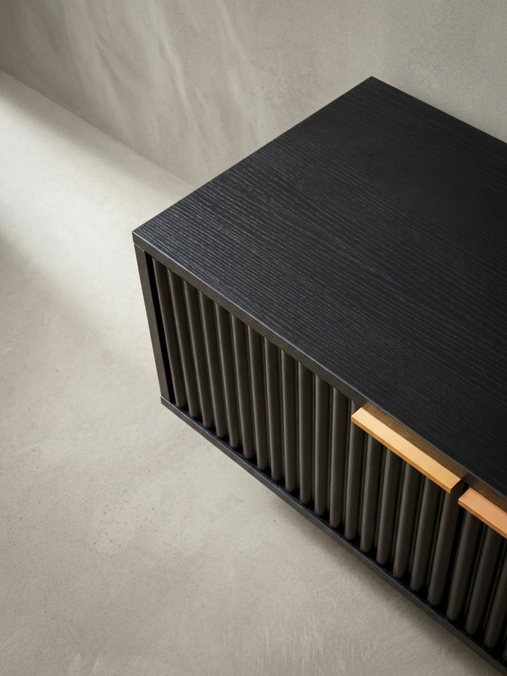 Makroaufnahme eines der eleganten, goldenen Griffe auf der geriffelten Tür des TV-Schranks, ein Detail des modernen Designs._