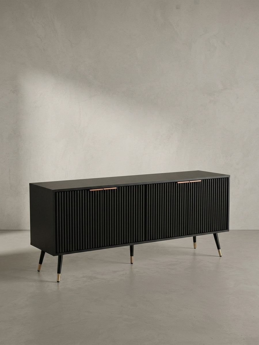 Frontansicht des schwarzen TV-Lowboards 150x60 cm mit vier geriffelten Türen und dezenten Messinggriffen, freigestellt vor neutralem Hintergrund._