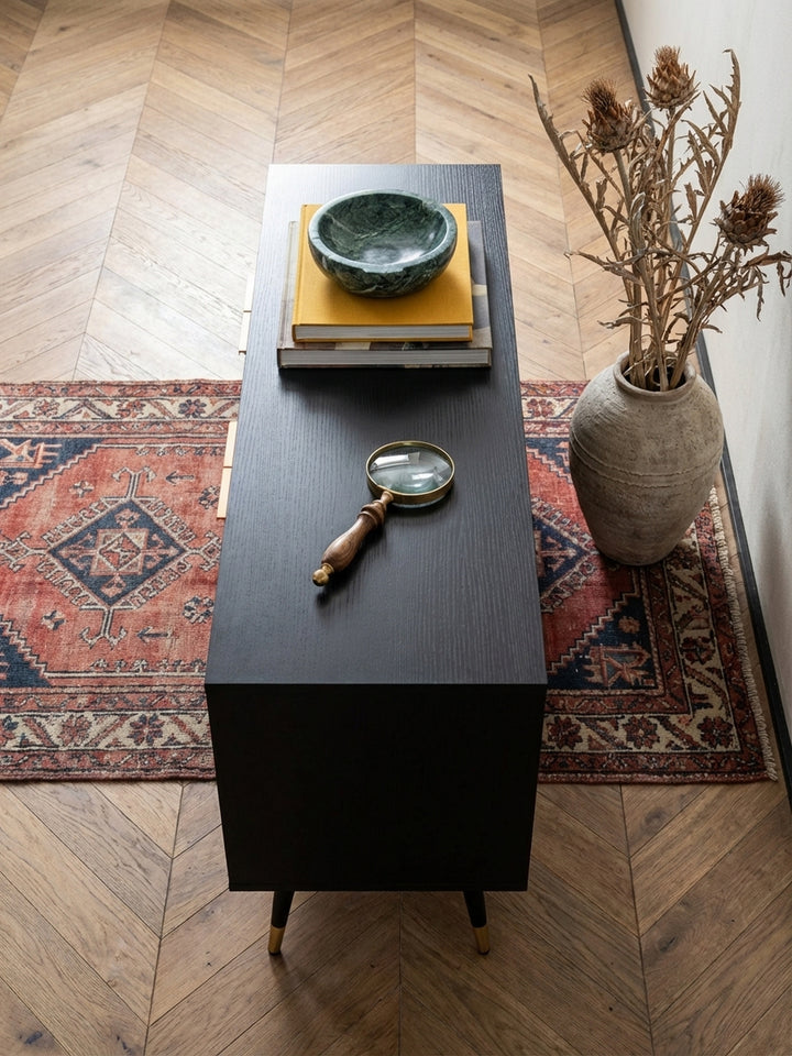 Blick von oben auf ein stilvolles Wohnzimmer-Arrangement mit einem 150 cm breiten Fernsehschrank in Schwarz und einem cognacfarbenen Ledersessel._