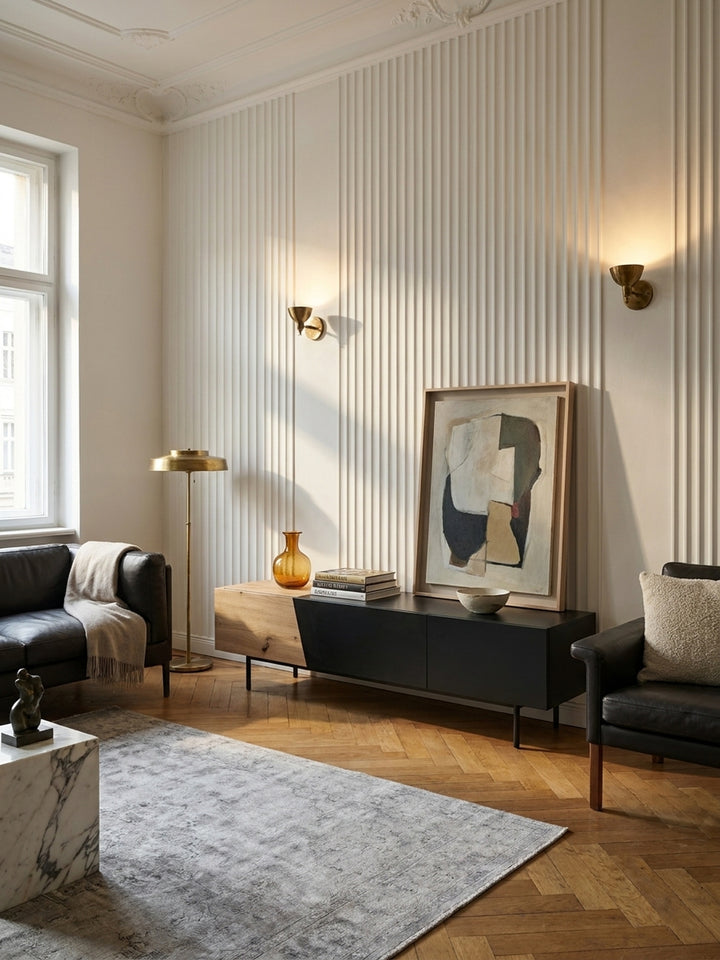 Modernes Lowboard für das Medienzimmer geschickt kombiniert mit einem beigen Leinensofa und einem messingfarbenen Beistelltisch vor einer warmweißen Altbauwand._