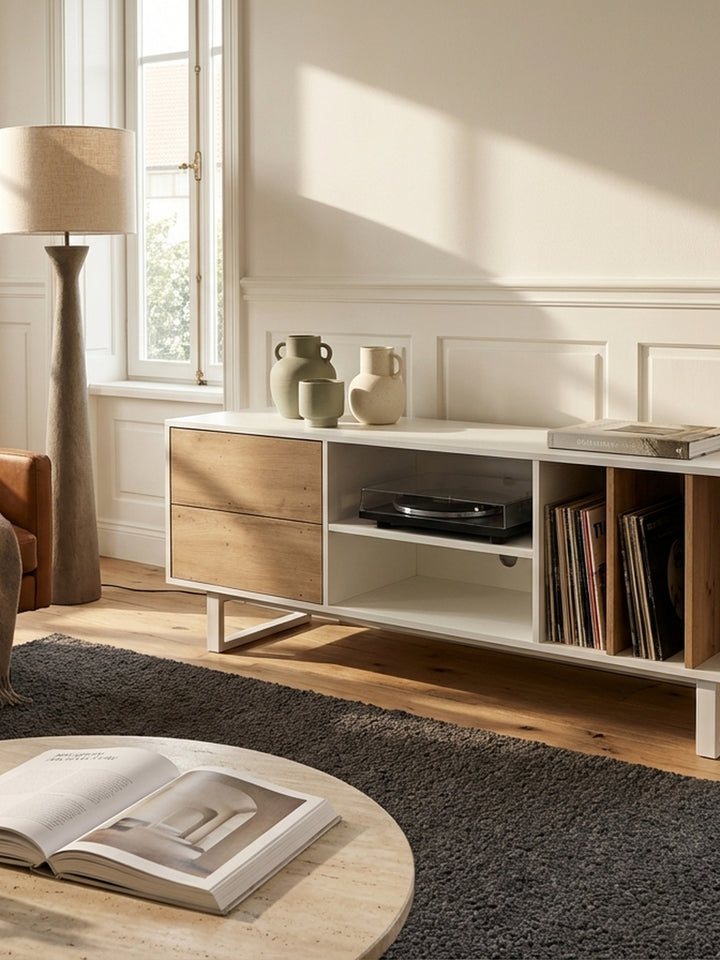 Ein minimalistisches Stillleben auf dem weißen TV-Sideboard: ein Stapel Kunstbücher neben einer kleinen Keramikschale, beleuchtet von sanftem Tageslicht._
