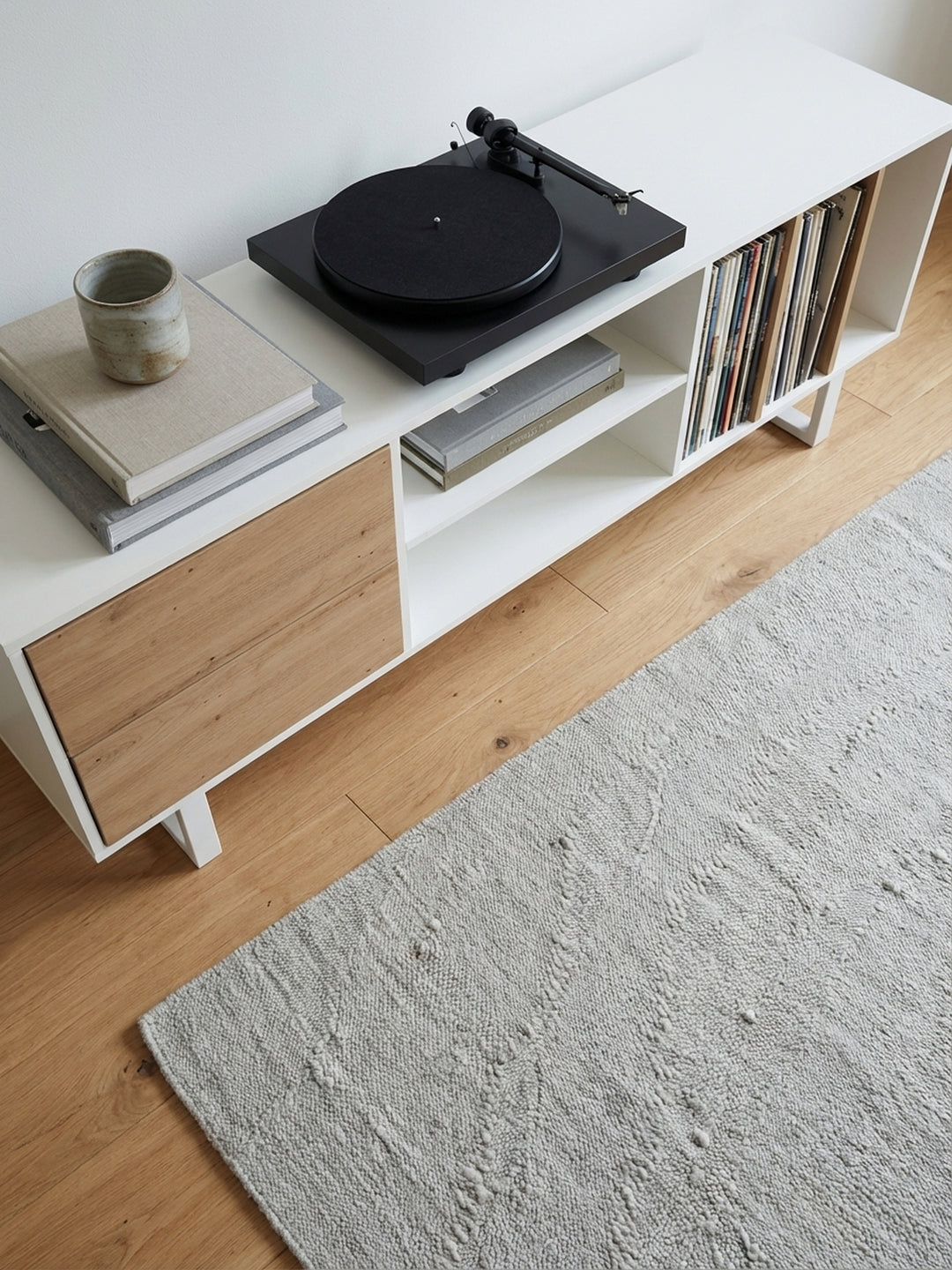 Draufsicht auf ein stilvolles Wohnzimmer-Arrangement mit dem 150 cm breiten TV-Schrank, der perfekt unter einem wandmontierten Fernseher positioniert ist._