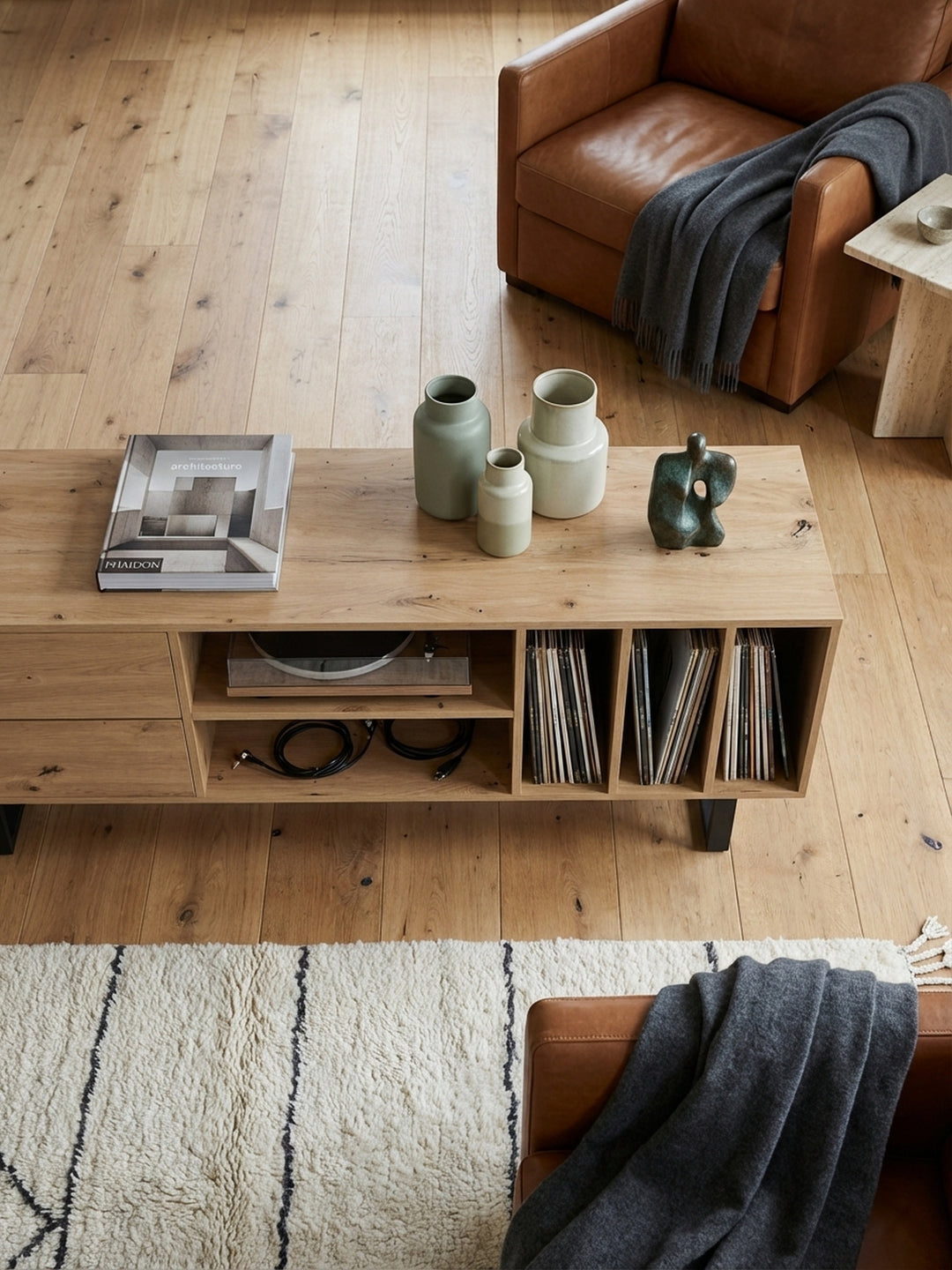 TV-Schrank aus Eichenholz-Dekor von oben betrachtet, zeigt die Anordnung mit Schallplatten, Büchern und einem Plattenspieler im minimalistisch eingerichteten Wohnbereich._