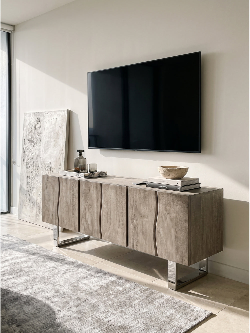 Detailansicht des TV-Schranks in Smoked Grey mit einem schweren Bildband über Architektur und einem rauchgrauen Glasdekanter._