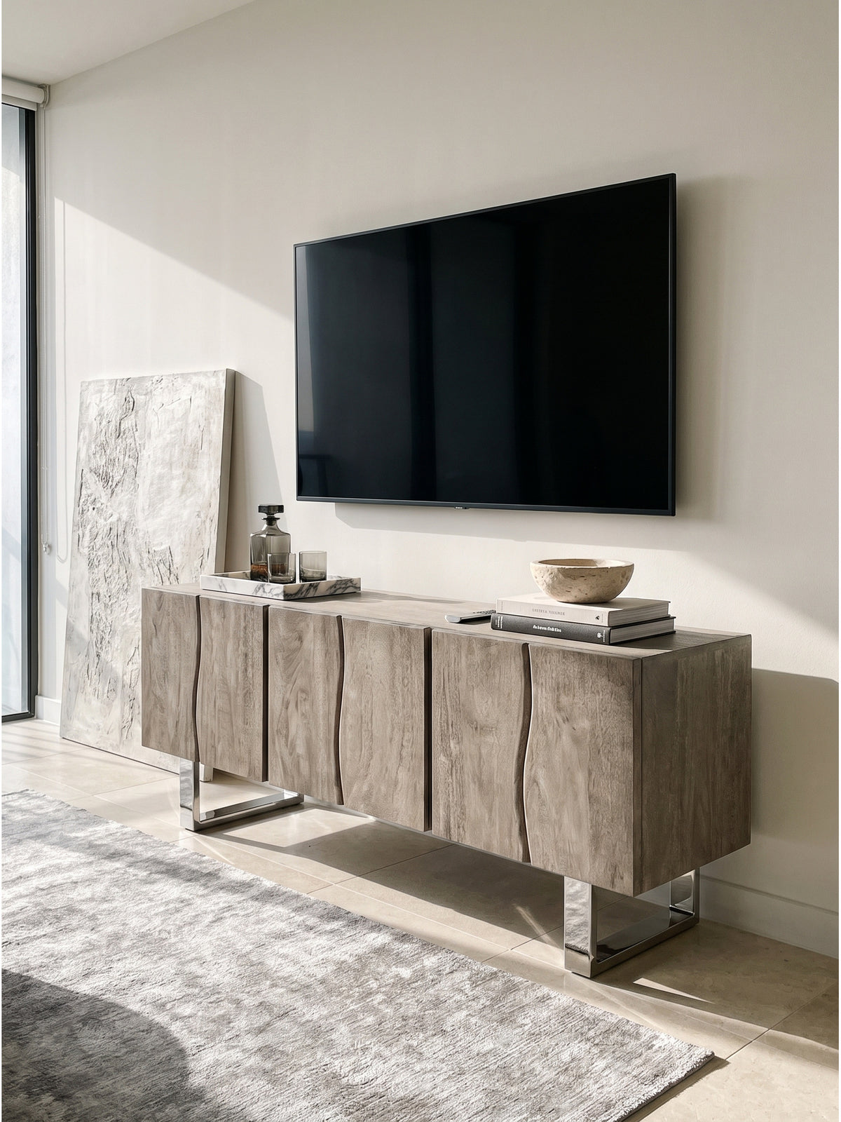 Detailansicht des TV-Schranks in Smoked Grey mit einem schweren Bildband über Architektur und einem rauchgrauen Glasdekanter._