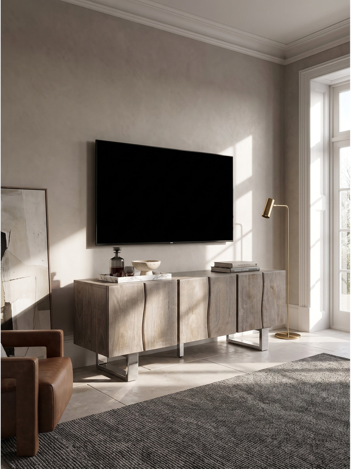 Minimalistisches Wohnzimmer mit TV-Lowboard aus sandgestrahlter Akazie und polierten Chromfüßen auf großformatigem Kalksteinboden.