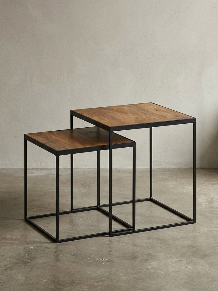 Design Beistelltisch 2er-Set aus massivem Mangoholz und schwarzem Metallgestell, frontal fotografiert vor neutralem Hintergrund, um die klaren Linien zu zeigen._