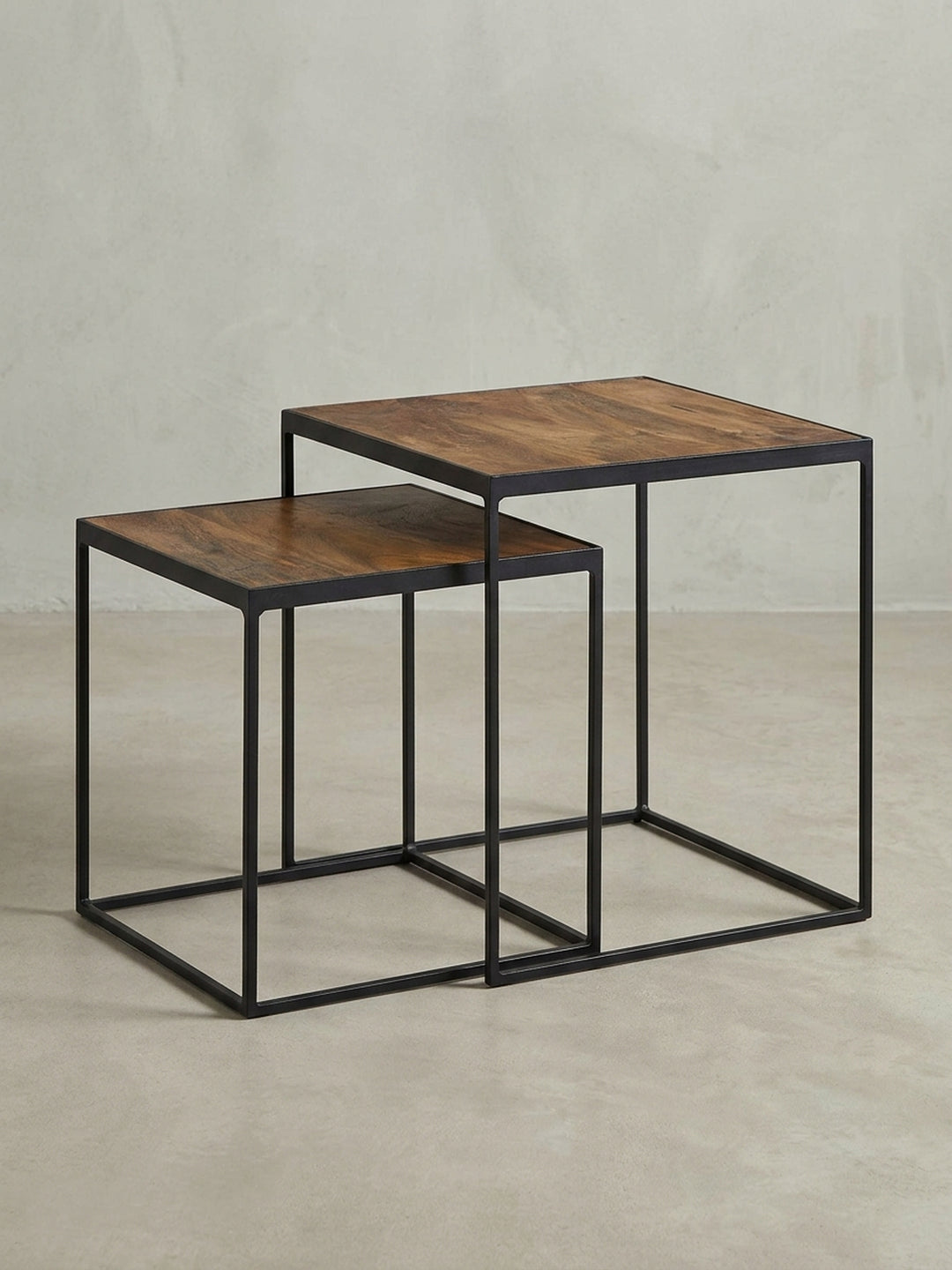 Industrial Couchtisch 2er-Set aus der Dreiviertelperspektive, die die harmonische Kombination aus warmer Mangoholz-Tischplatte und kühlem Metallgestell zeigt._