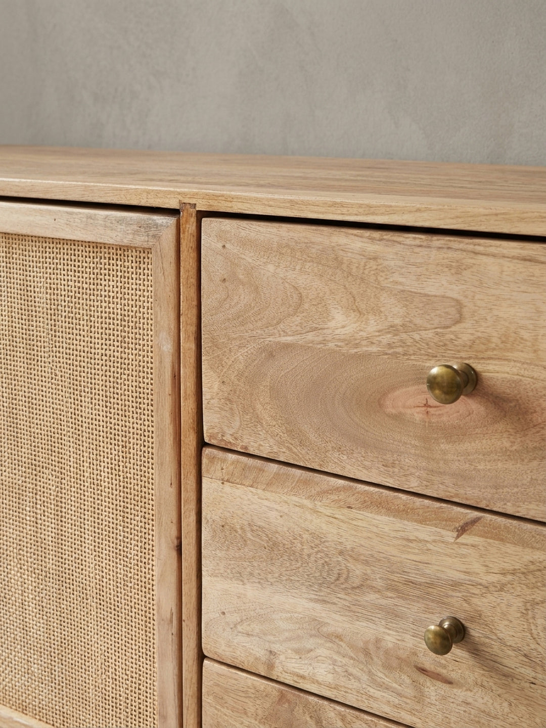 Nahaufnahme eines goldenen Metallgriffs an einer Schublade des Sideboards. Der Kontrast zwischen dem warmen Mangoholz und dem glänzenden Griff unterstreicht den Retro-Stil._