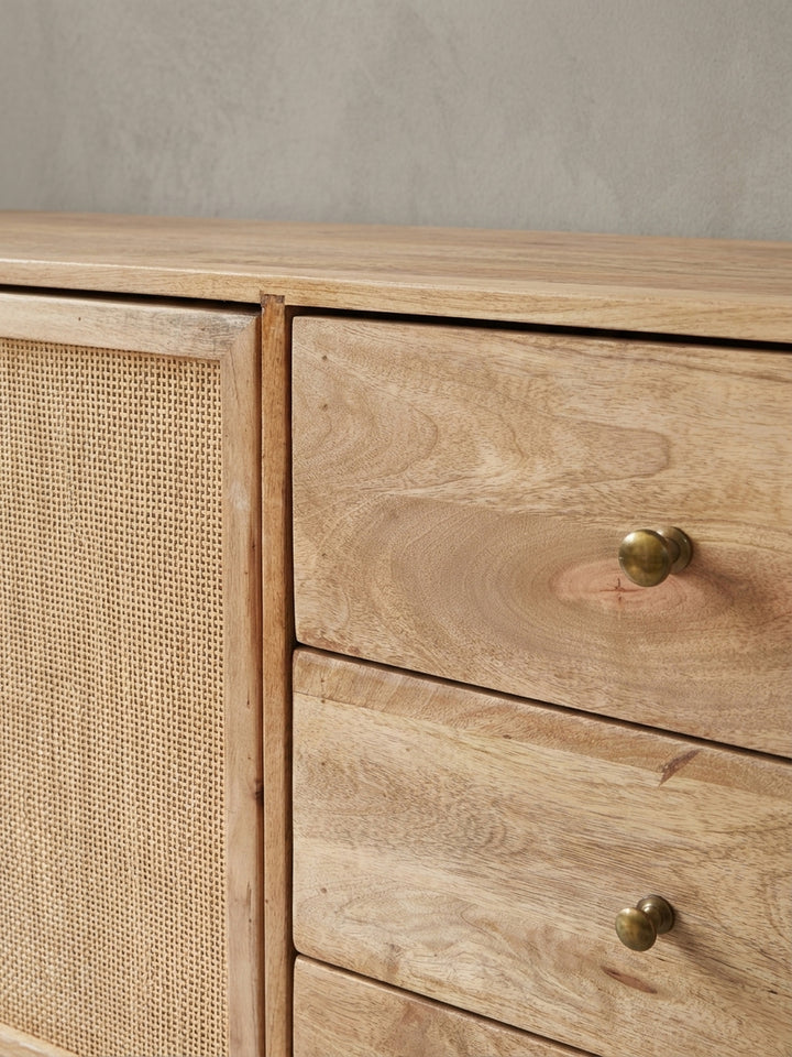 Nahaufnahme eines goldenen Metallgriffs an einer Schublade des Sideboards. Der Kontrast zwischen dem warmen Mangoholz und dem glänzenden Griff unterstreicht den Retro-Stil._
